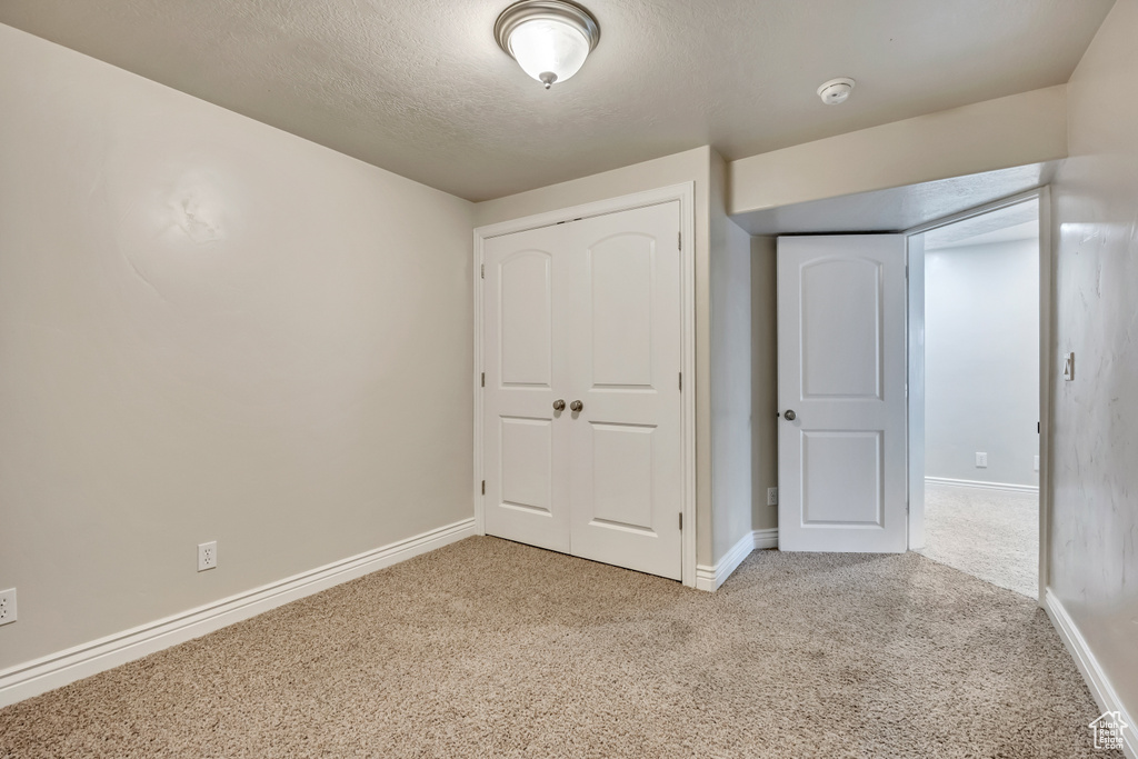 Unfurnished bedroom featuring carpet flooring, baseboards, a closet, and a textured ceiling