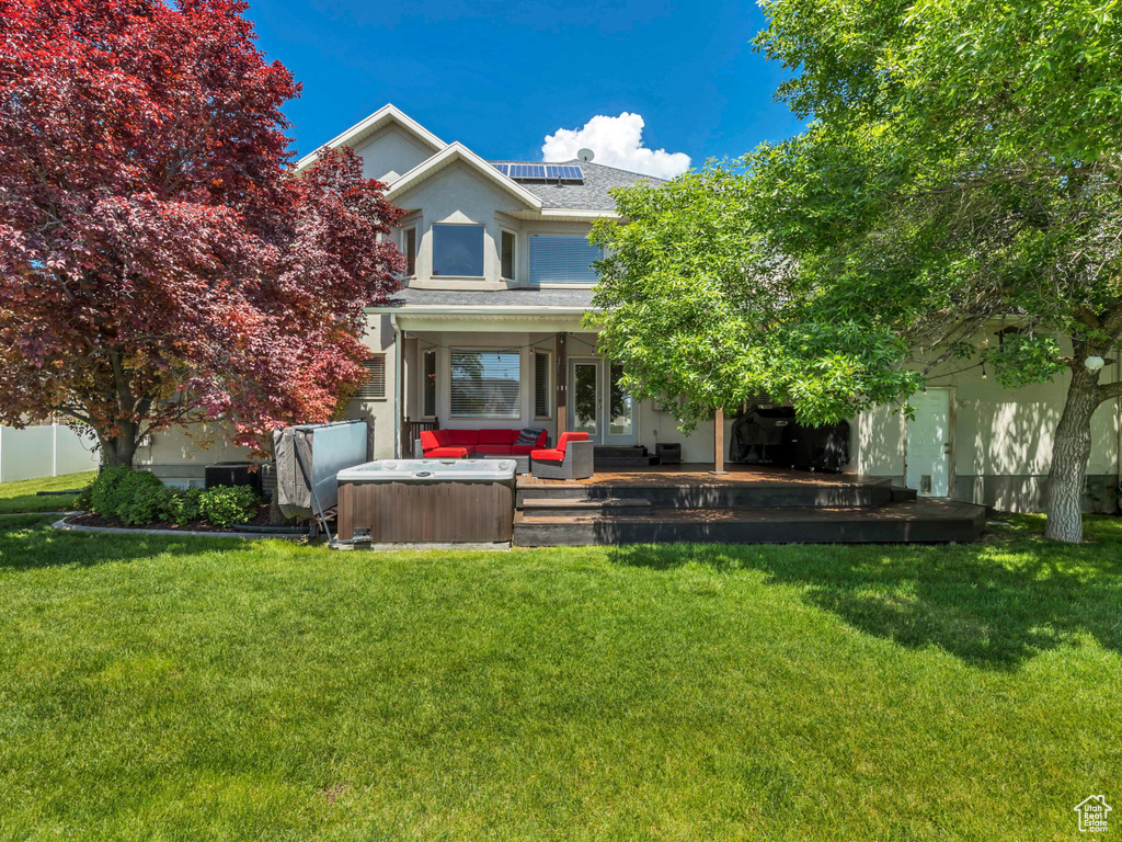View of front of property featuring a hot tub, solar panels, a shingled roof, and stucco siding