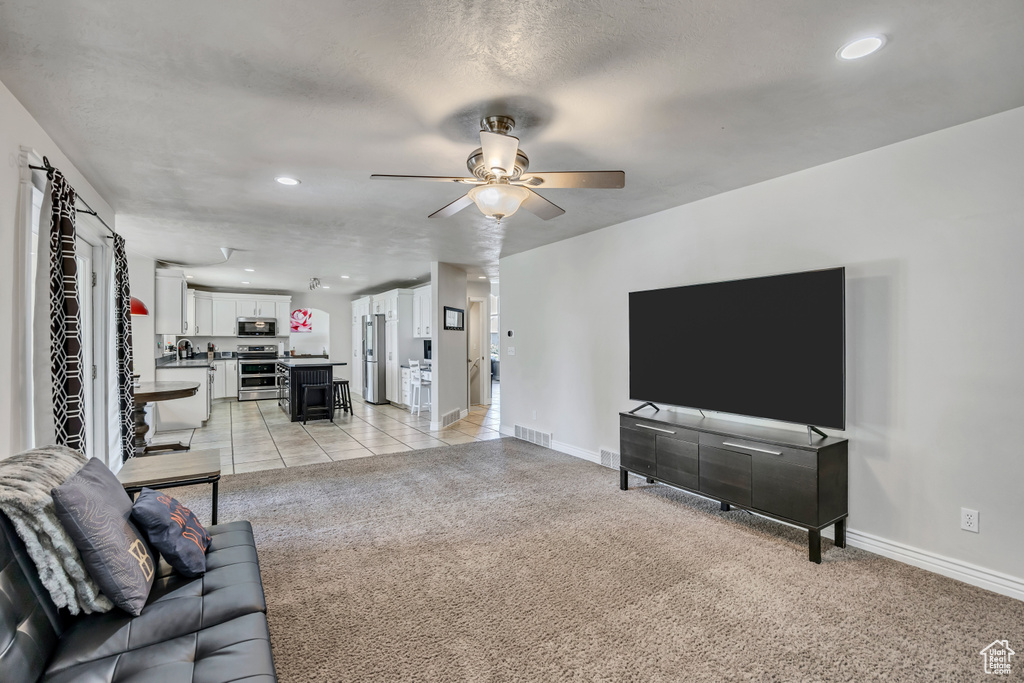 Living room featuring ceiling fan, baseboards, light carpet, and recessed lighting