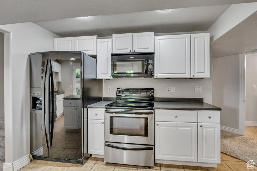 Kitchen with black appliances, white cabinetry, and dark countertops