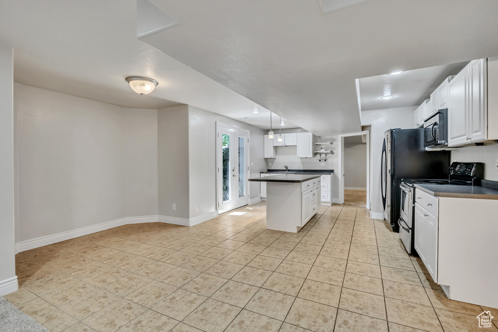 Kitchen with stainless steel appliances, dark countertops, light tile patterned floors, and white cabinets