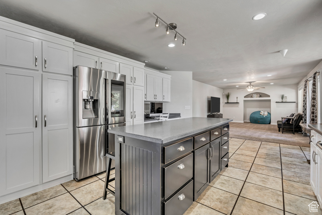 Kitchen featuring stainless steel refrigerator with ice dispenser, light tile patterned floors, ceiling fan, recessed lighting, and a center island