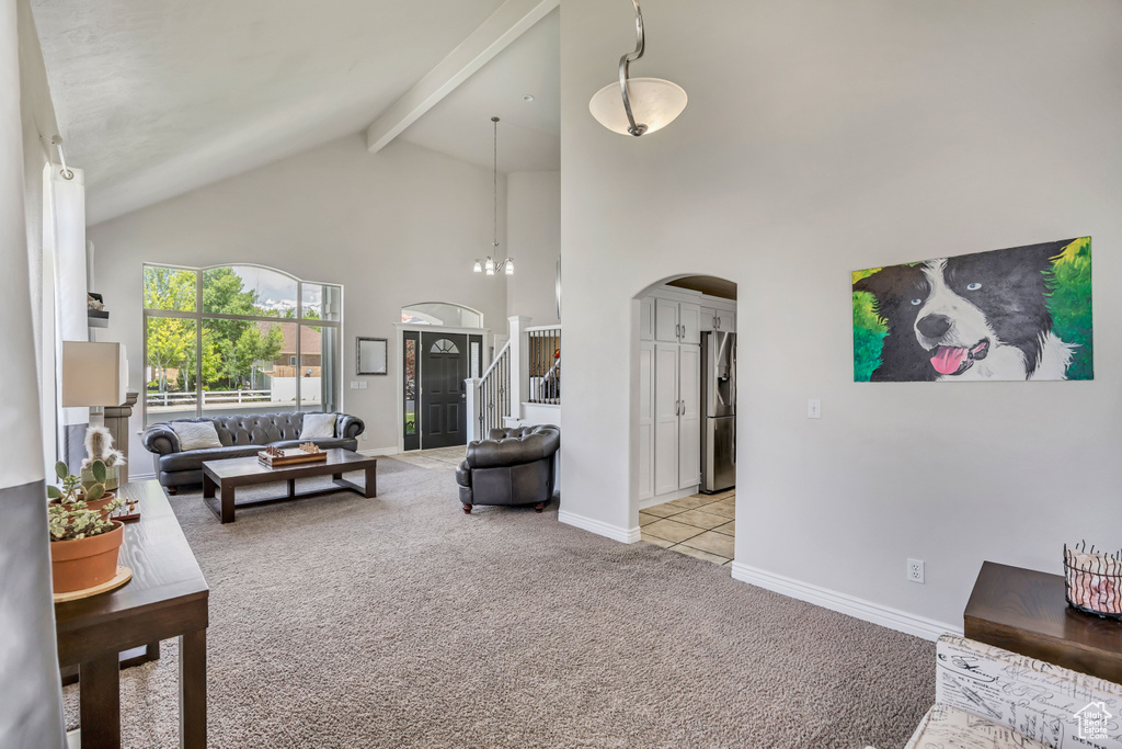 Carpeted living room featuring high vaulted ceiling, arched walkways, beam ceiling, stairs, and baseboards