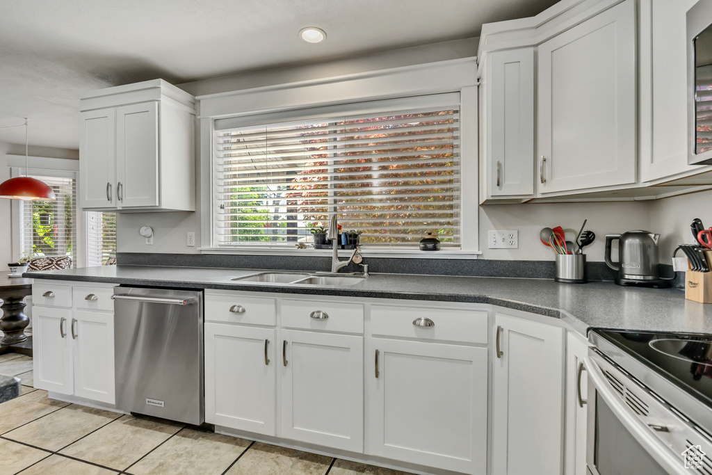 Kitchen featuring stainless steel appliances, dark countertops, healthy amount of natural light, light tile patterned floors, and recessed lighting