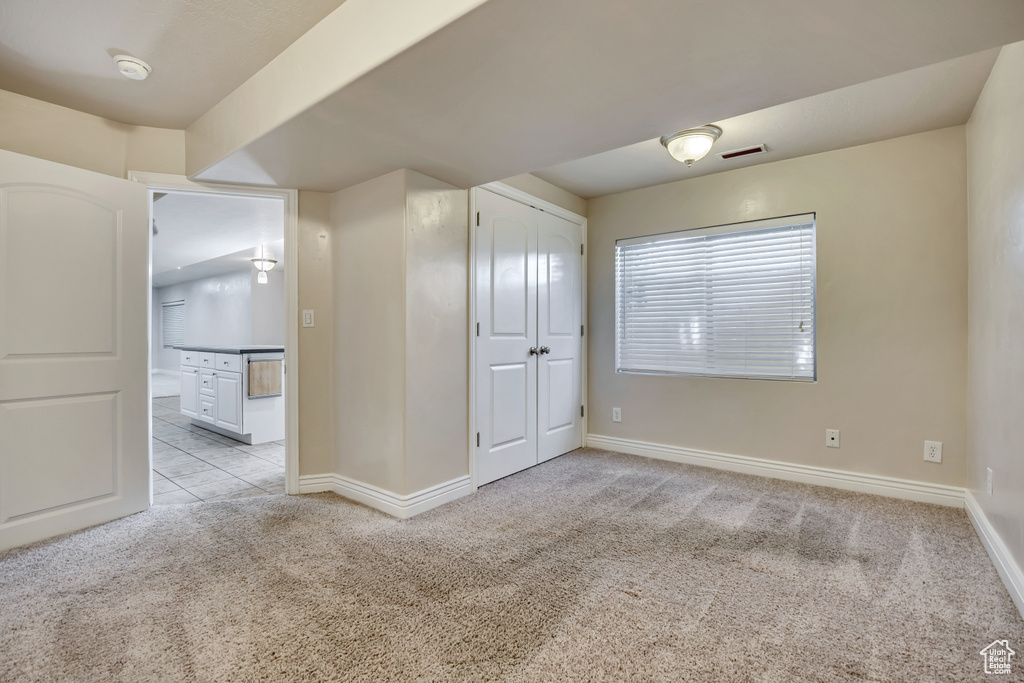 Unfurnished bedroom with light carpet, baseboards, and ensuite bath