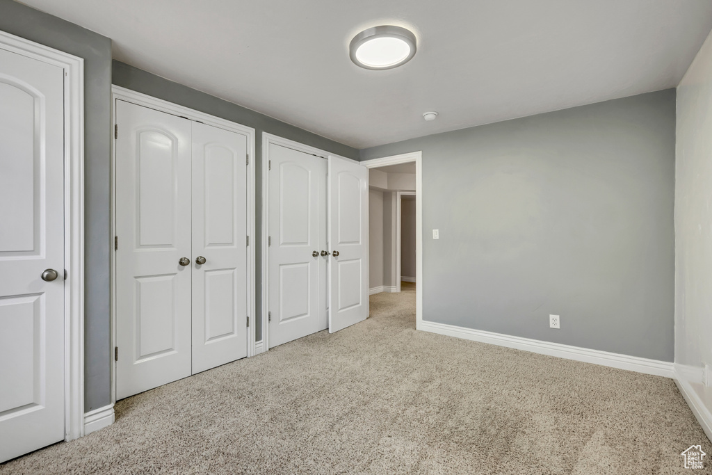 Unfurnished bedroom with multiple closets, carpet flooring, and baseboards