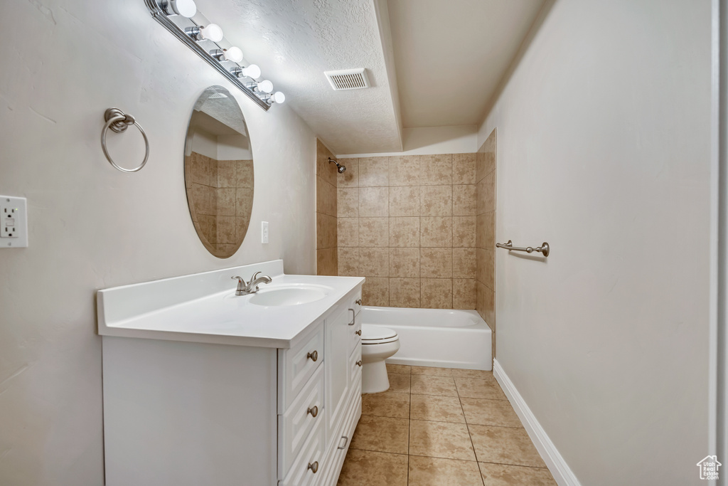 Bathroom featuring toilet, vanity, tile patterned floors, and  shower combination