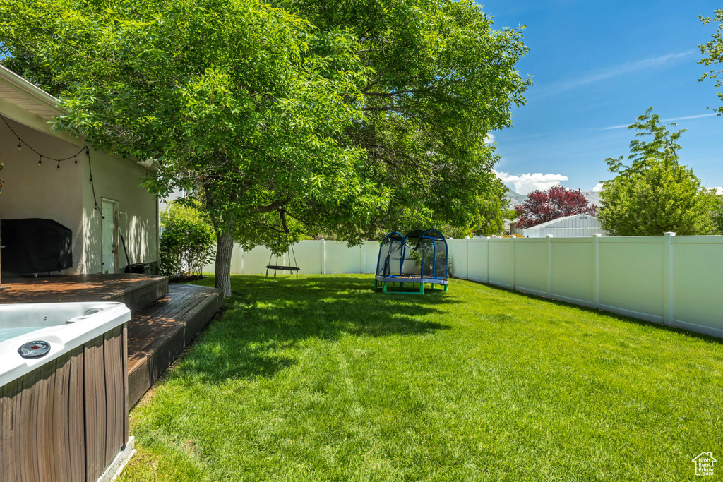 View of yard featuring a trampoline and a hot tub