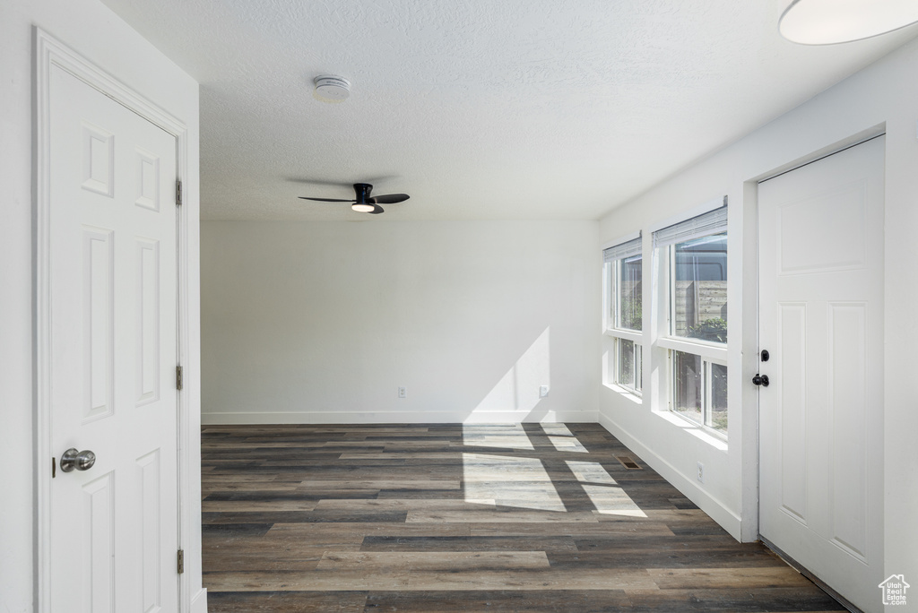 Spare room featuring baseboards, a smoke detector, ceiling fan, dark wood finished floors, and a textured ceiling