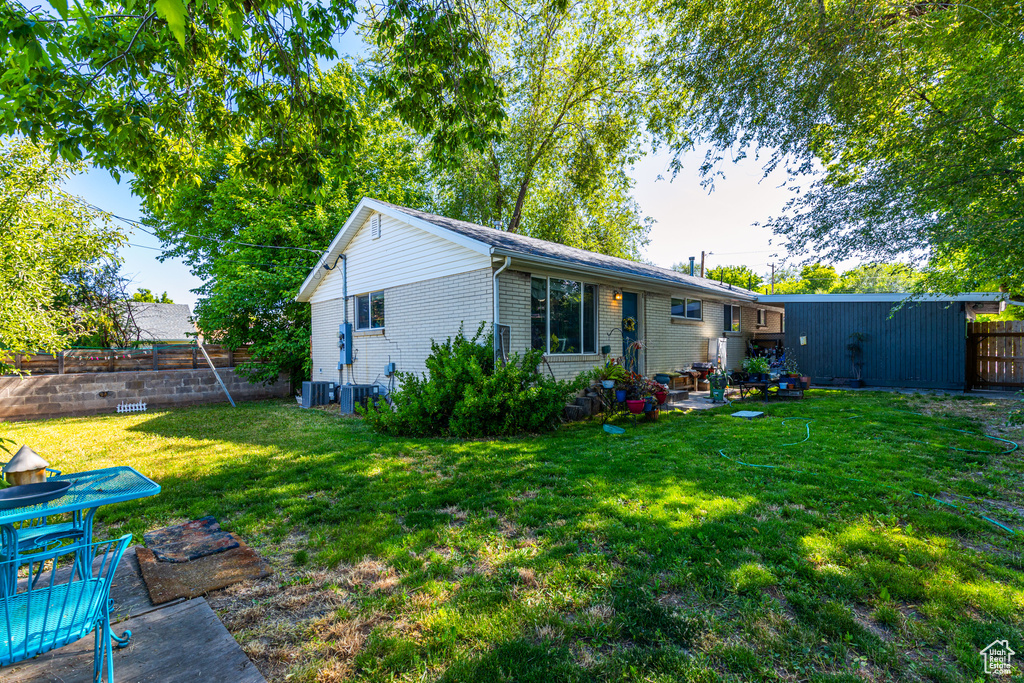 Rear view of house featuring brick siding, central AC unit, and a patio
