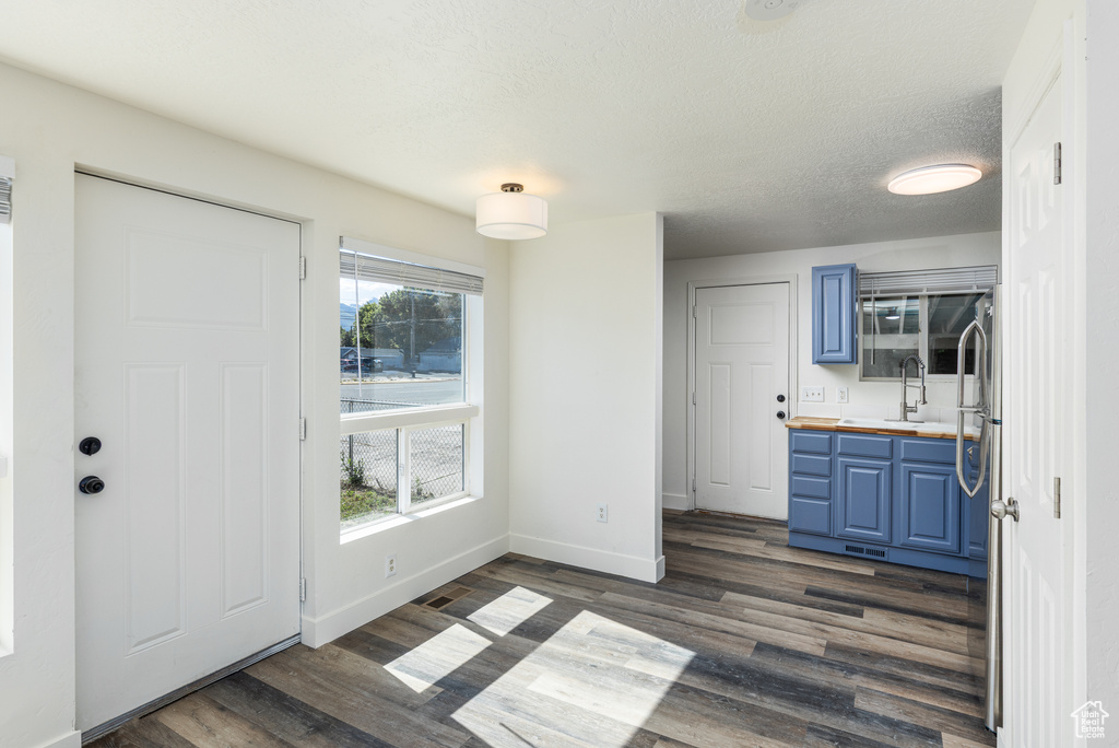 Unfurnished dining area featuring dark wood-style floors, a sink, and baseboards