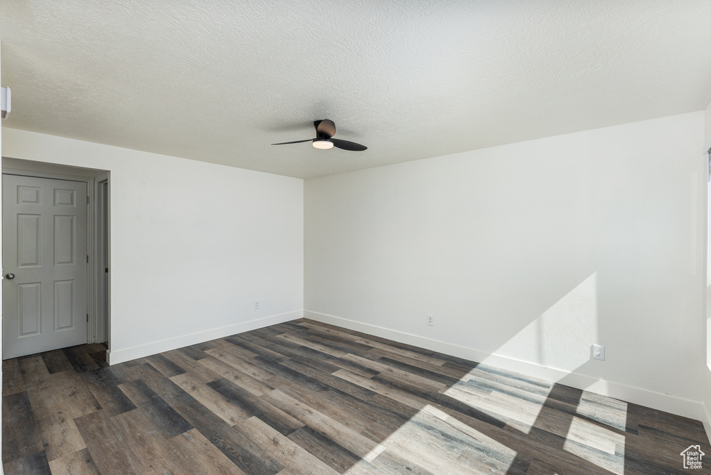 Unfurnished room with a ceiling fan, dark wood-style flooring, baseboards, and a textured ceiling