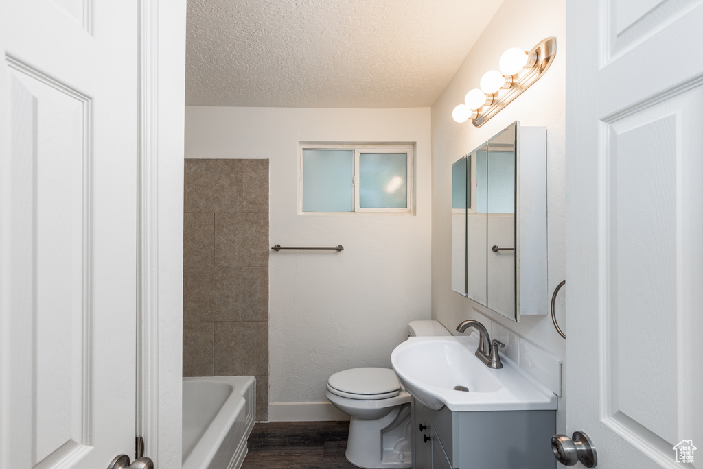 Bathroom with vanity, a textured ceiling, toilet, baseboards, and wood finished floors