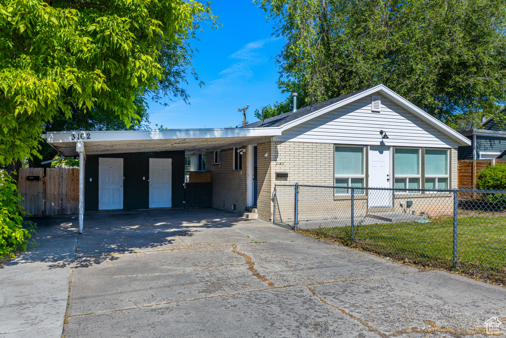 Ranch-style home with driveway, brick siding, and a carport