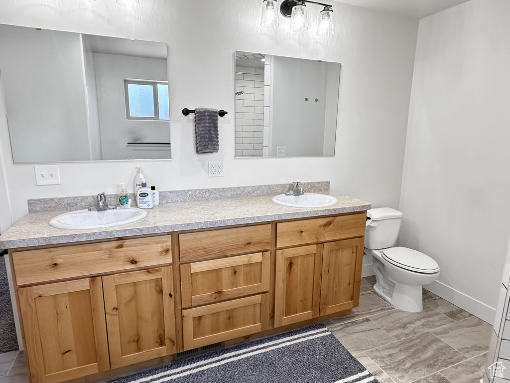 Full bath featuring double vanity, toilet, and baseboards