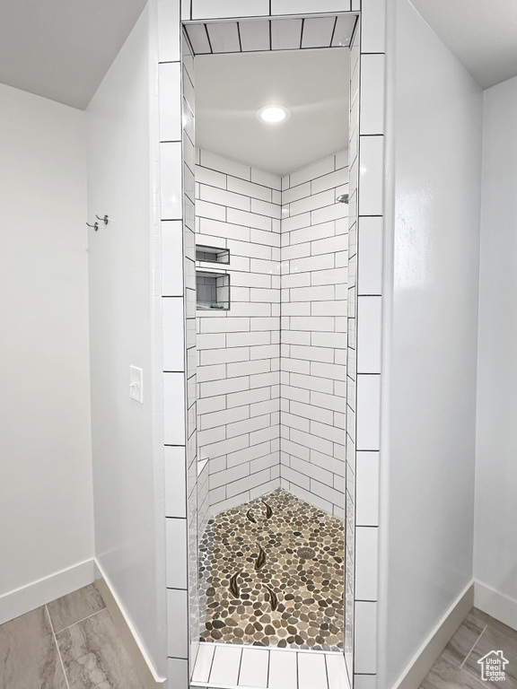 Full bath featuring a shower stall, baseboards, and marble finish flooring
