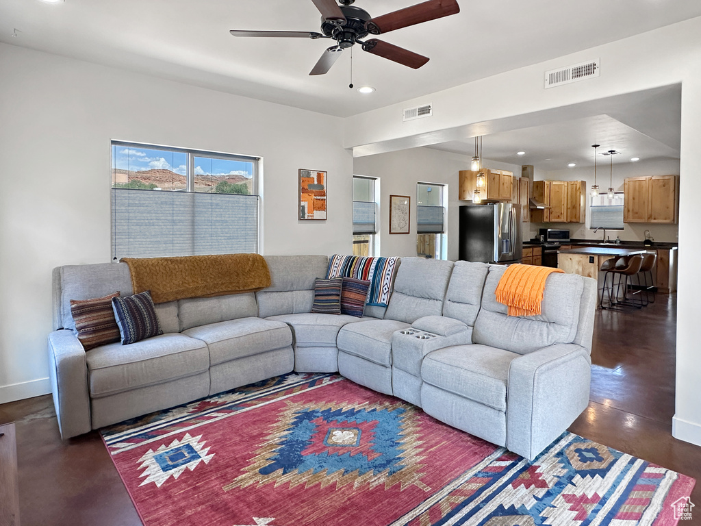 Living area featuring recessed lighting, a ceiling fan, concrete floors, and baseboards