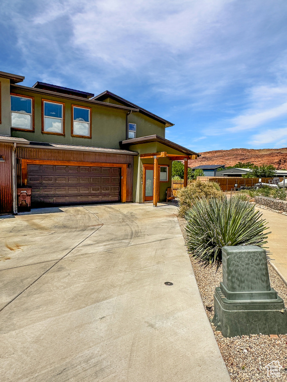 View of front of property featuring an attached garage, concrete driveway, stucco siding, and a mountain view
