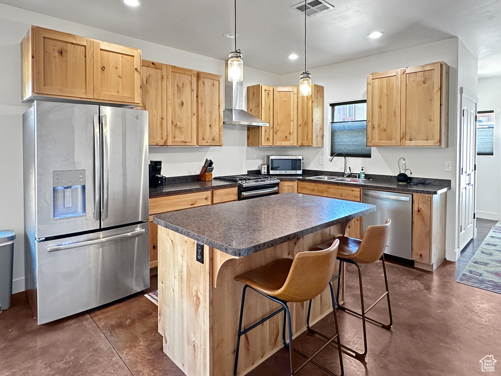 Kitchen featuring stainless steel appliances, a sink, wall chimney range hood, dark countertops, and a center island