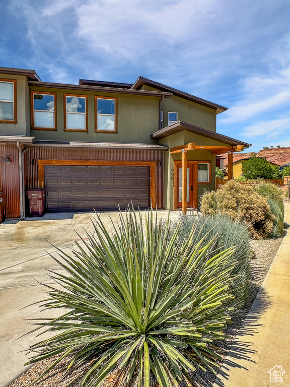 View of front of home featuring a garage, stucco siding, and driveway