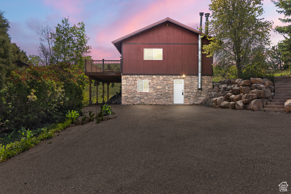 Property exterior at dusk with stone siding and a deck
