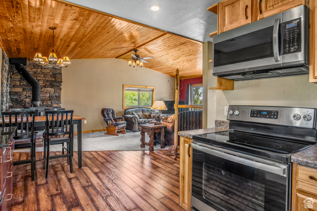 Kitchen featuring appliances with stainless steel finishes, a wood stove, lofted ceiling, wood ceiling, and a chandelier