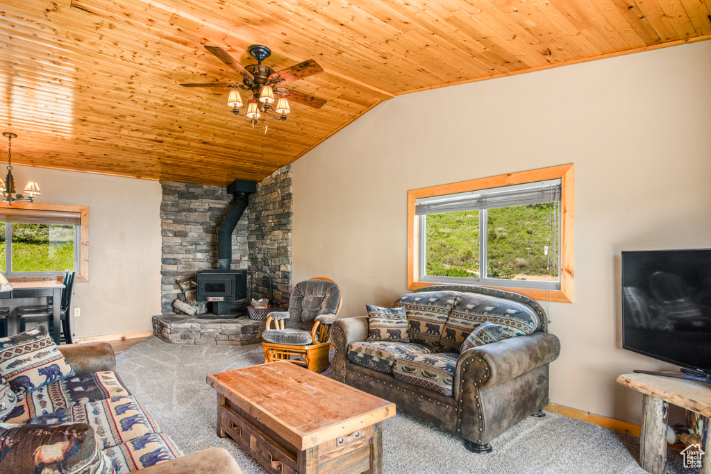 Living area featuring wood ceiling, a wood stove, vaulted ceiling, ceiling fan, and baseboards