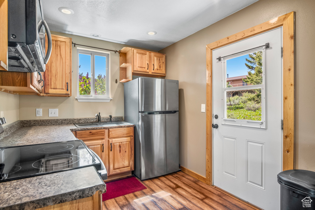 Kitchen with freestanding refrigerator, a sink, light wood finished floors, plenty of natural light, and recessed lighting
