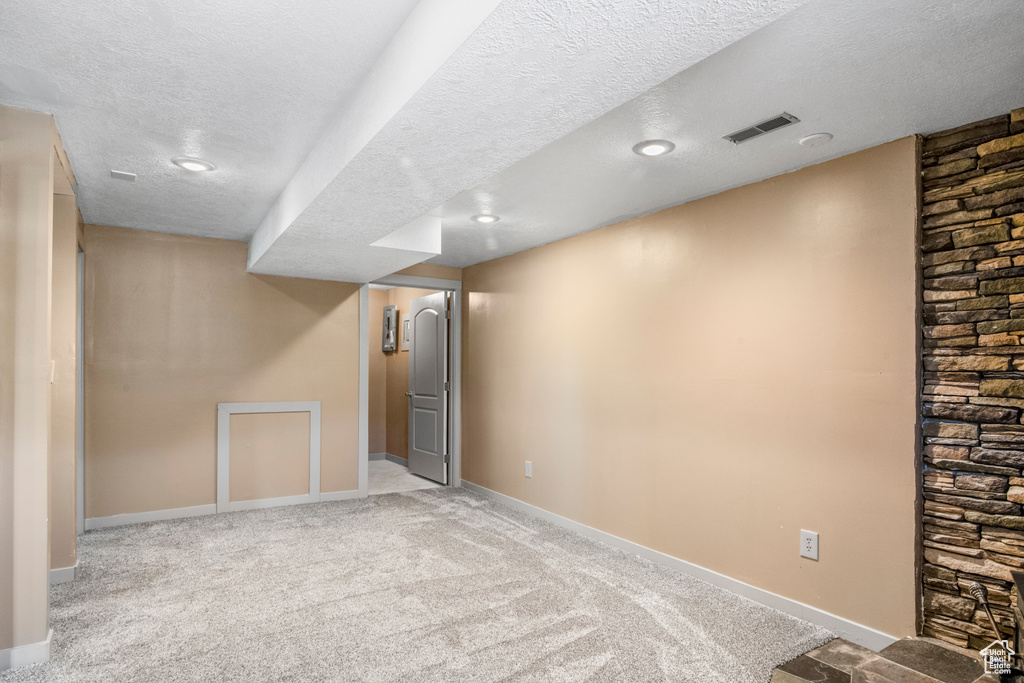 Finished below grade area with a textured ceiling, carpet floors, baseboards, and recessed lighting