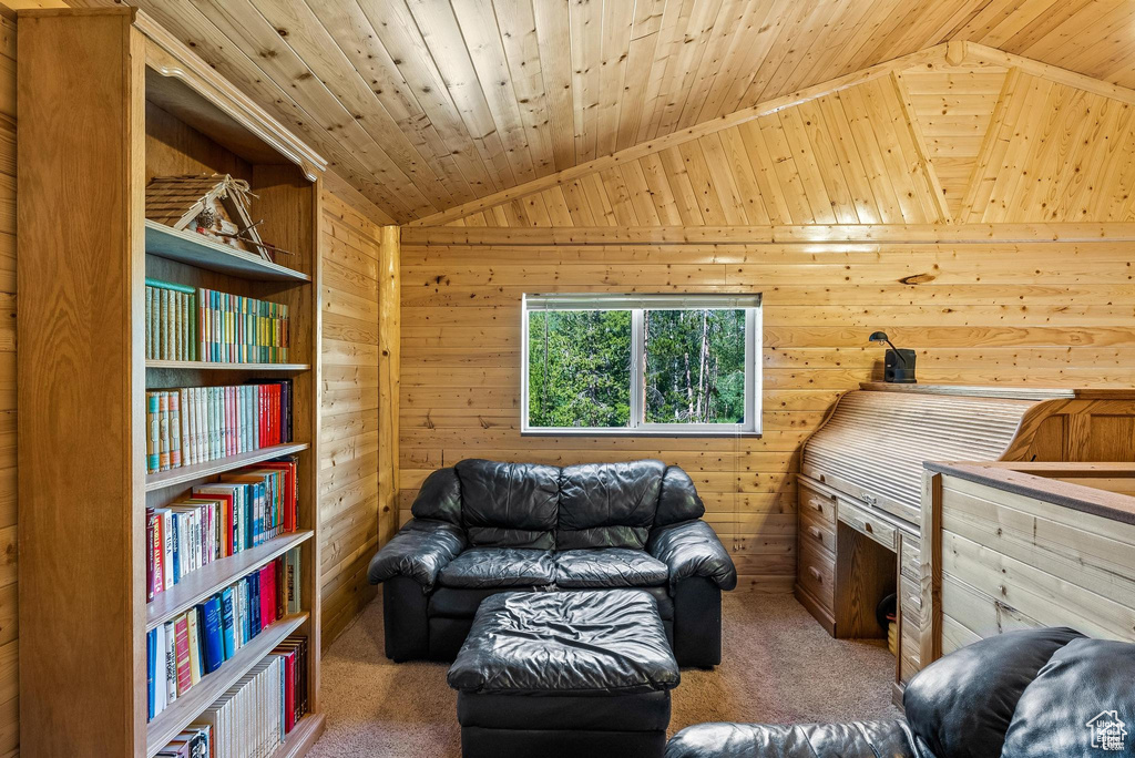 Carpeted living room with lofted ceiling, wood walls, and wooden ceiling