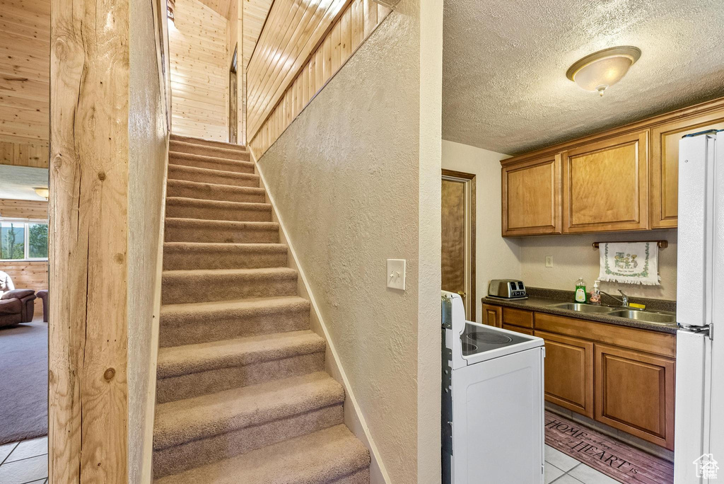 Stairway featuring a textured wall, a textured ceiling, and tile patterned floors