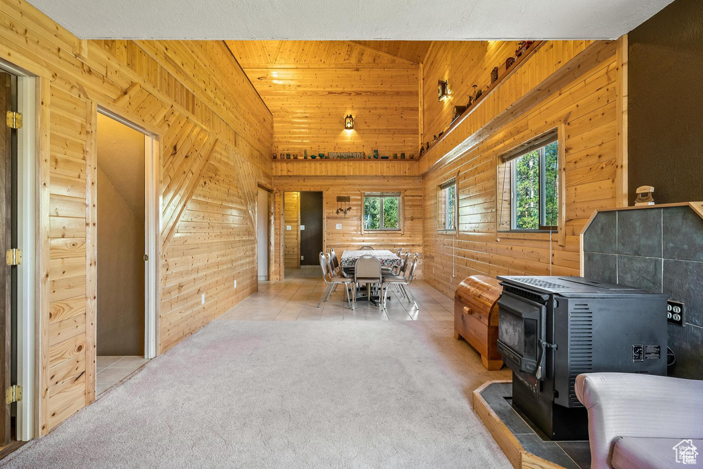 Interior space with a wood stove, wooden walls, and carpet floors