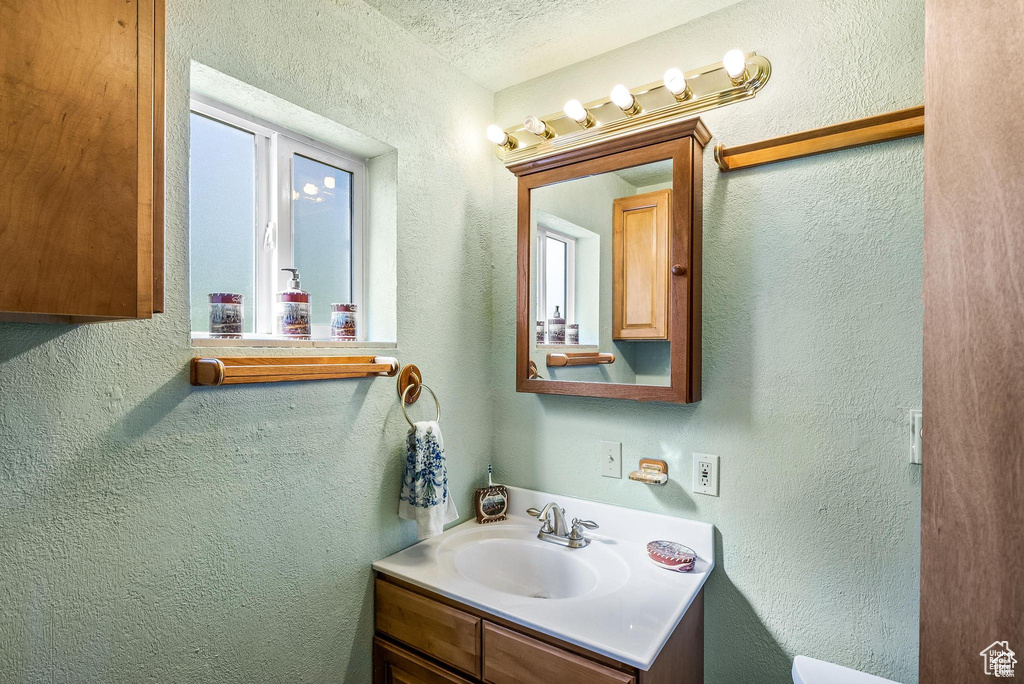 Bathroom featuring vanity, a textured wall, and a textured ceiling