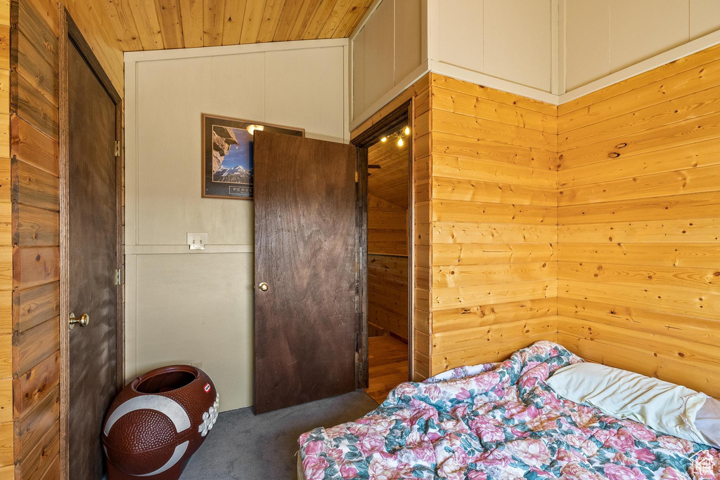 Bedroom with wood ceiling, carpet floors, and wood walls