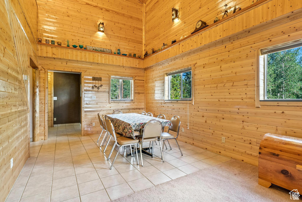 Dining area with wooden walls, light tile patterned floors, and a towering ceiling