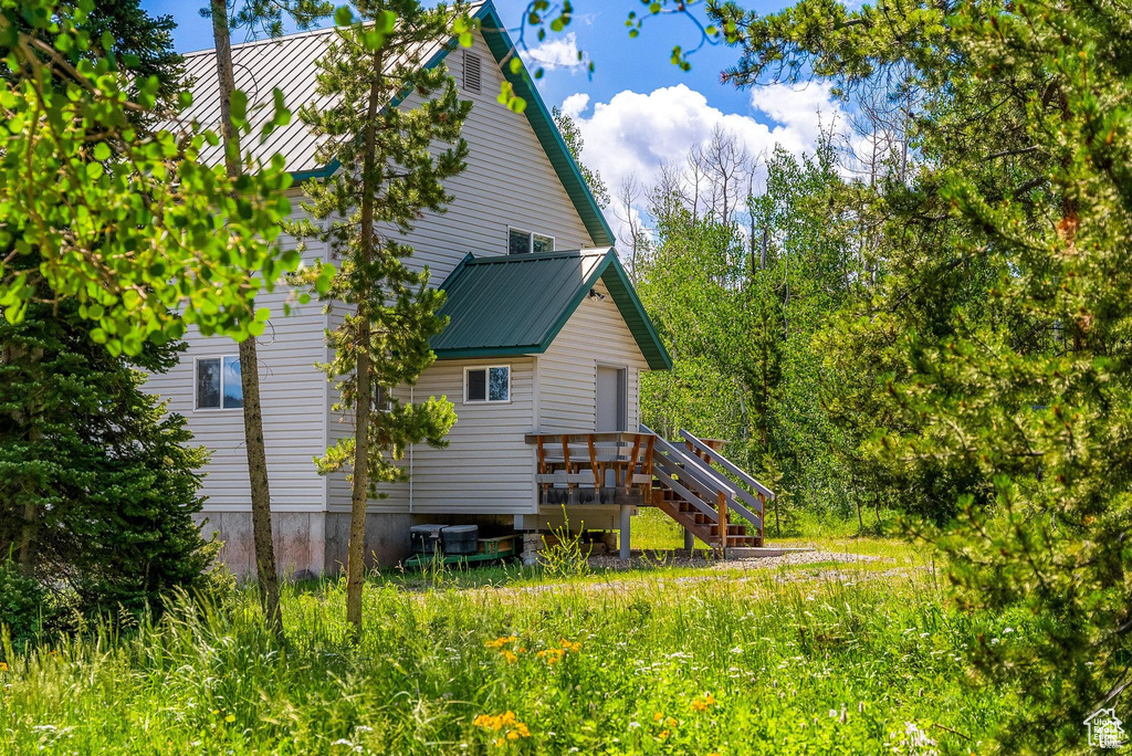 View of home\\\'s exterior with stairway, a wooden deck, and metal roof