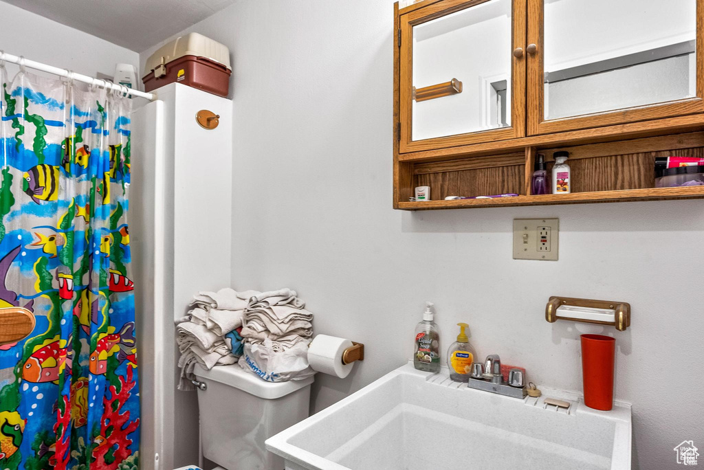 Bathroom with toilet, a sink, and a shower with shower curtain
