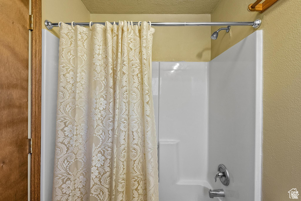 Full bathroom with shower / bath combo and a textured ceiling