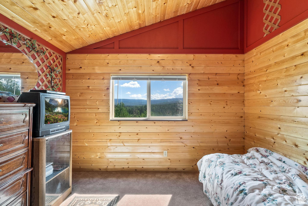 Bedroom with lofted ceiling, carpet, wooden walls, and wood ceiling