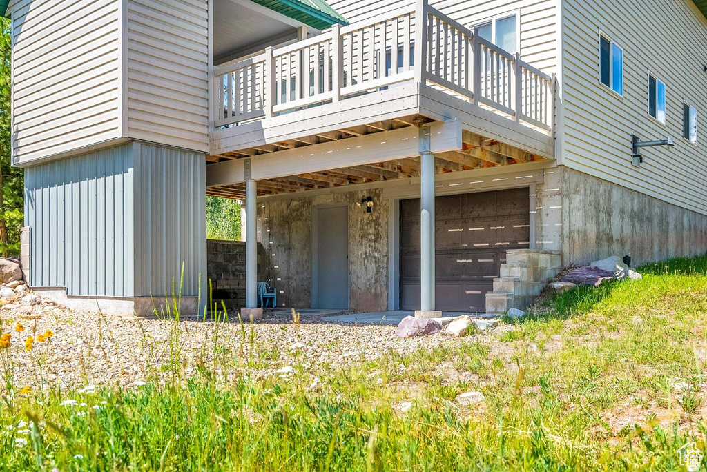 View of exterior entry featuring an attached garage and a wooden deck