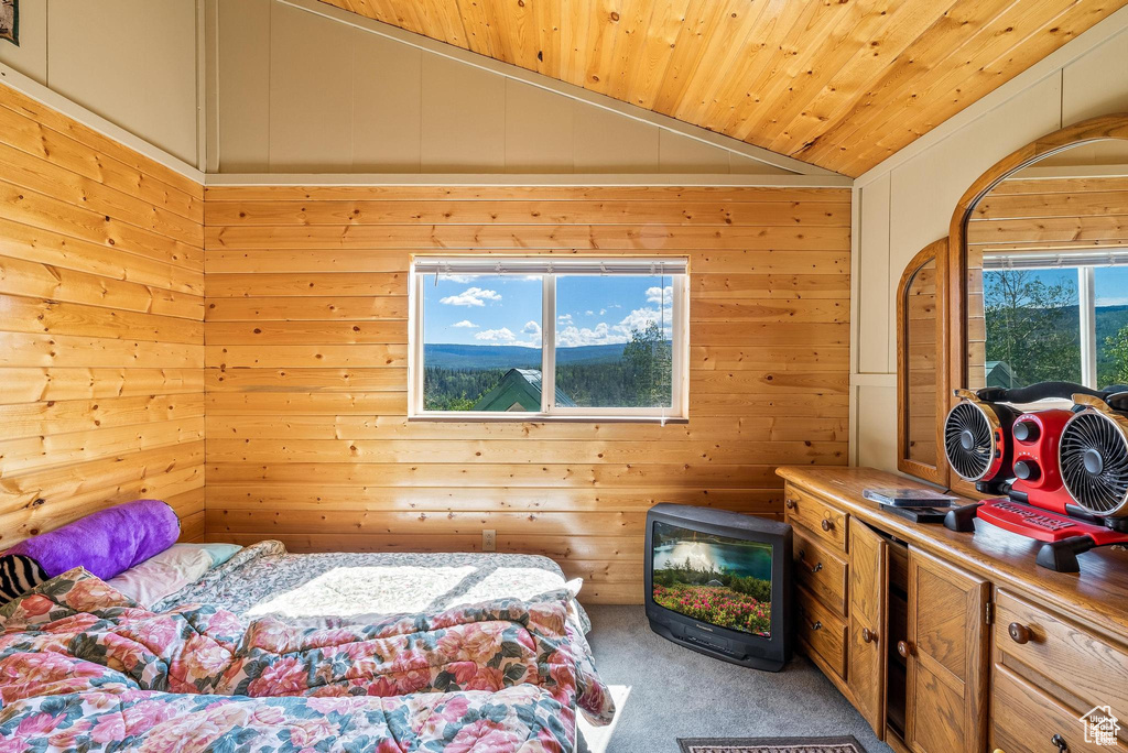 Carpeted bedroom with lofted ceiling, wood ceiling, and wood walls