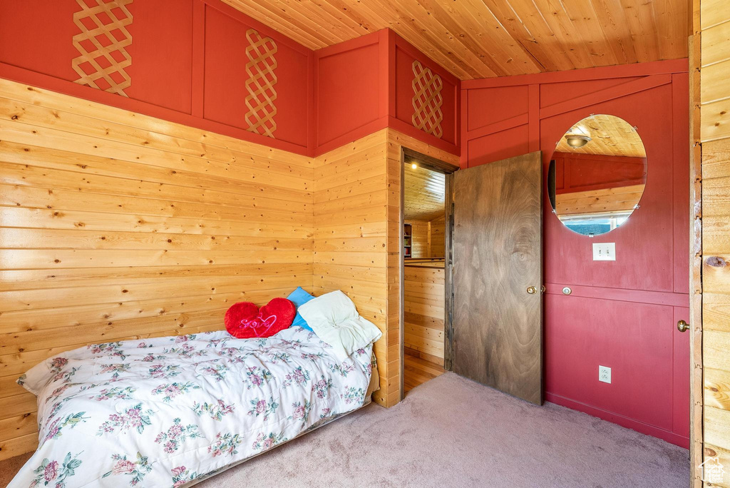 Carpeted bedroom with wood ceiling and wood walls