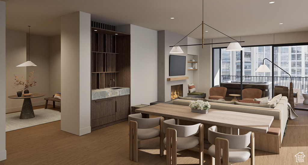 Dining area with light wood-style floors, a warm lit fireplace, and recessed lighting