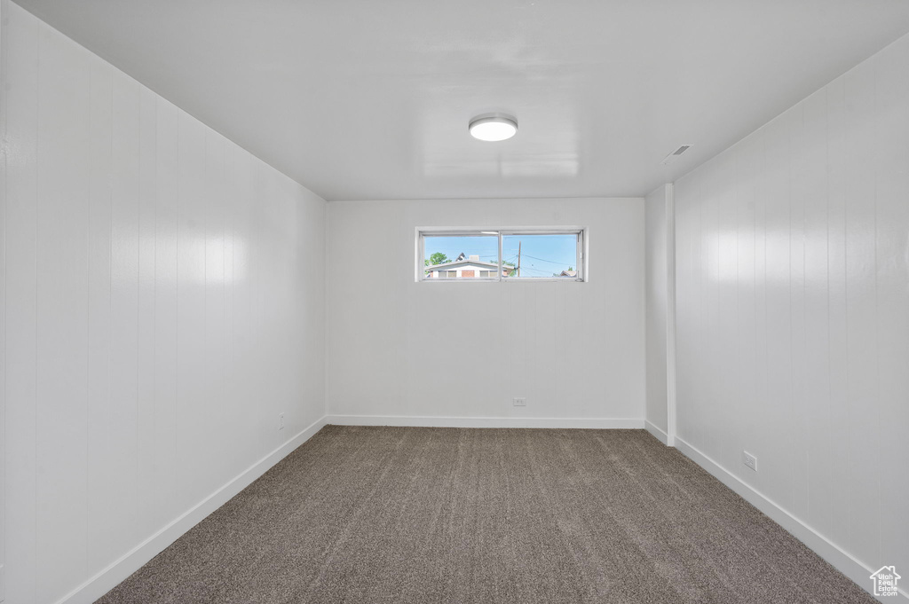 Spare room featuring dark colored carpet and baseboards