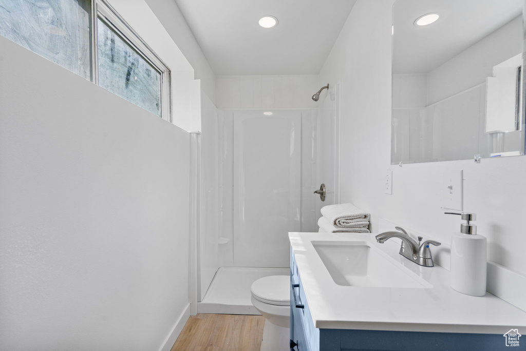Bathroom featuring toilet, a stall shower, wood finished floors, recessed lighting, and vanity