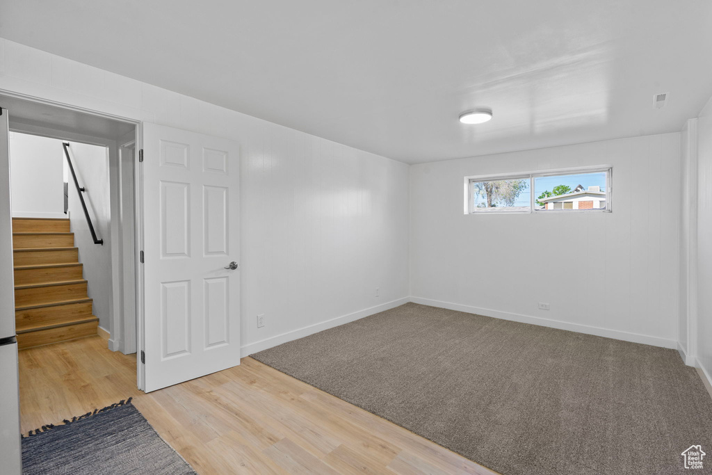 Basement featuring stairway, baseboards, and wood finished floors