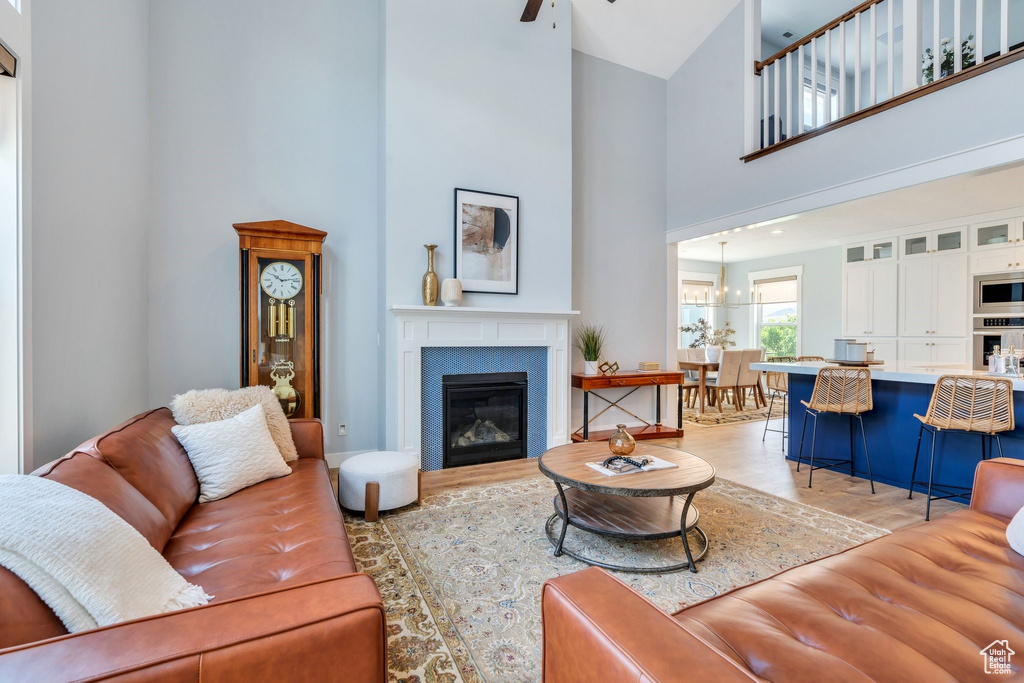 Living area featuring a high ceiling, light wood-style floors, and a glass covered fireplace