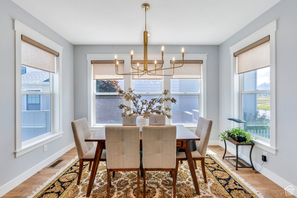 Dining space with a chandelier, baseboards, and light wood-type flooring