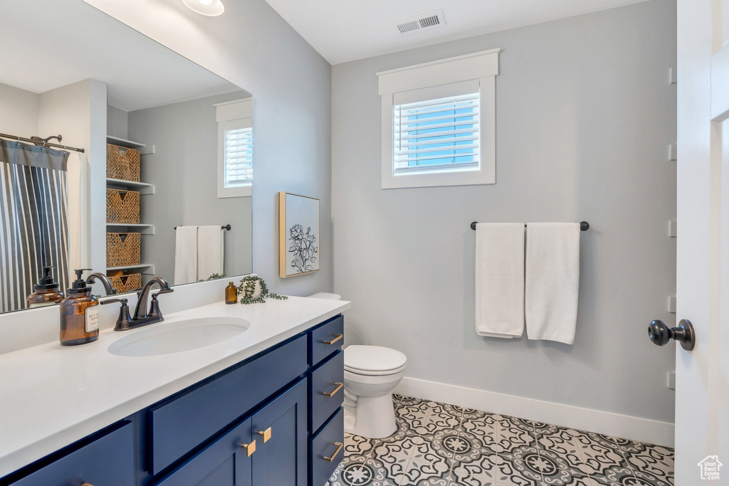 Bathroom with vanity, healthy amount of natural light, toilet, and baseboards