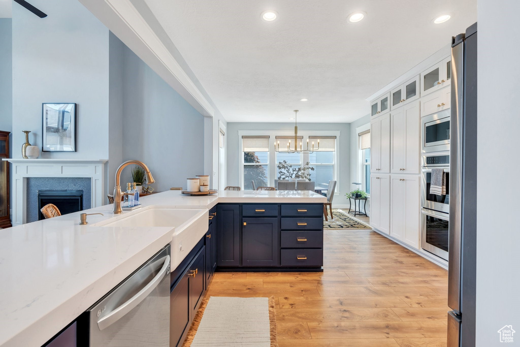 Kitchen featuring stainless steel appliances, a sink, light wood-style flooring, white cabinets, and recessed lighting